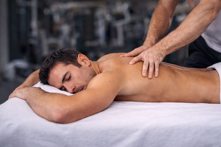 Αθλητικό μασάζ πλάτης σε άνδρα κατά τη διάρκεια συνεδρίας αποκατάστασης